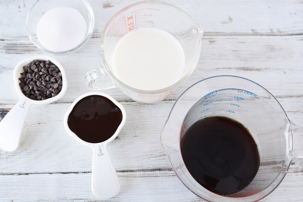 Milk, sugar, chips, coffee, and syrup in measuring cups. 