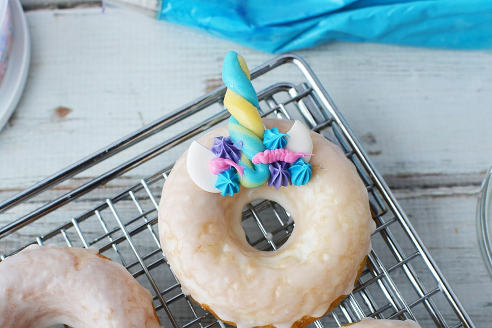 Donut on a rack with frosting and candy horn and ears.