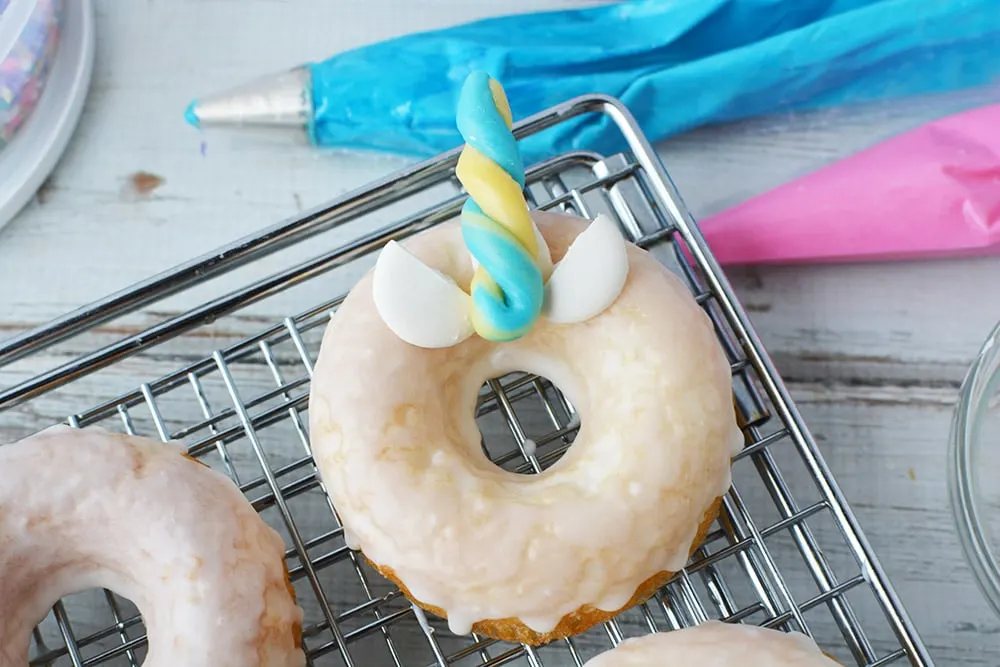 Donut with candy horn and ears with frosting bag.