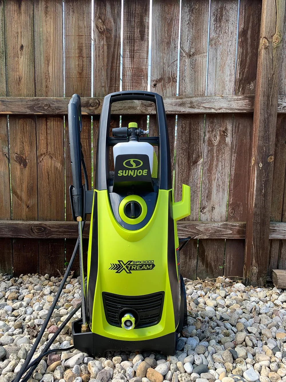 Sun Joe power washer in front of a fence. 