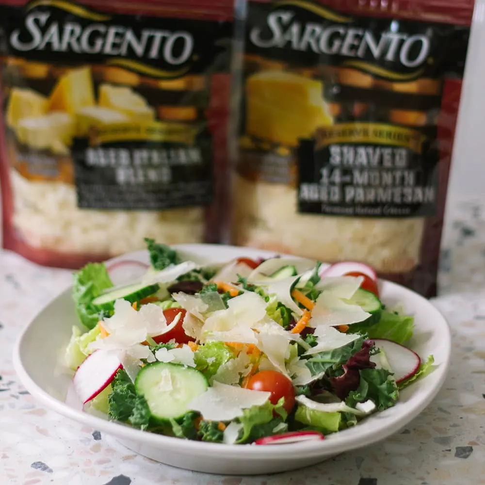 Salad in front of cheese packages.