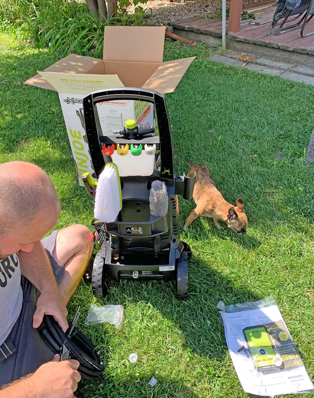 Man sitting on grass assembling the powerwasher. 