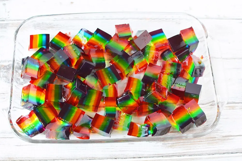 Rainbow jello cubes in a glass pan.