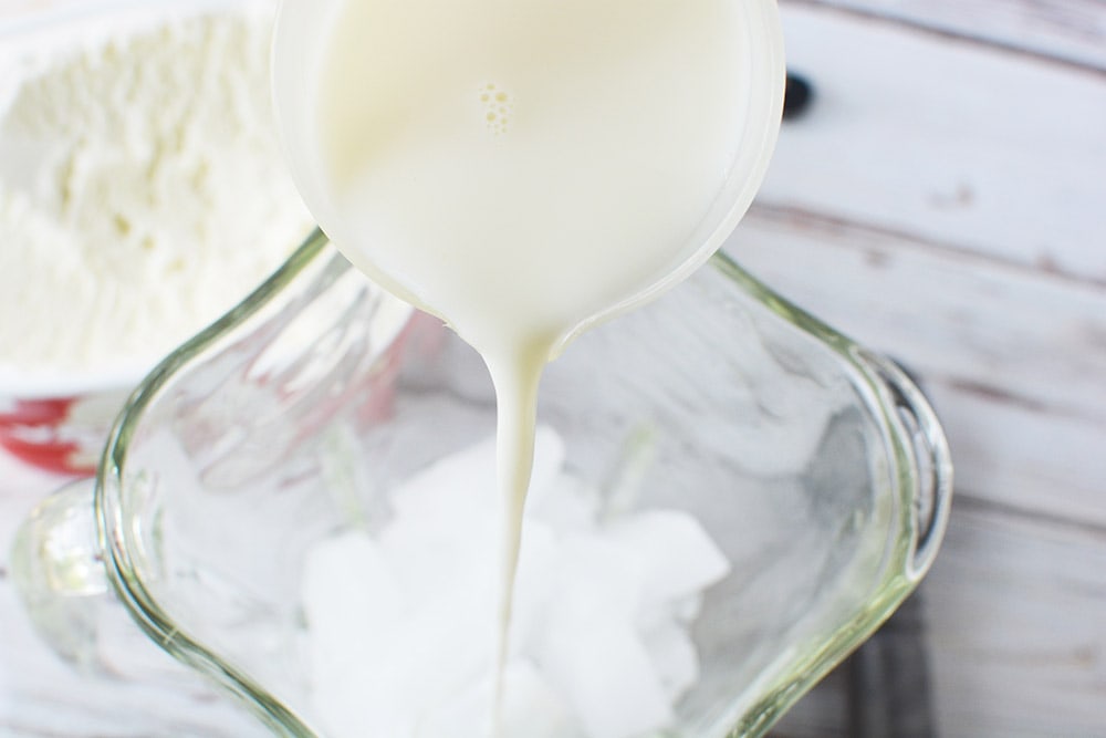 Pouring milk into a blender with ice.