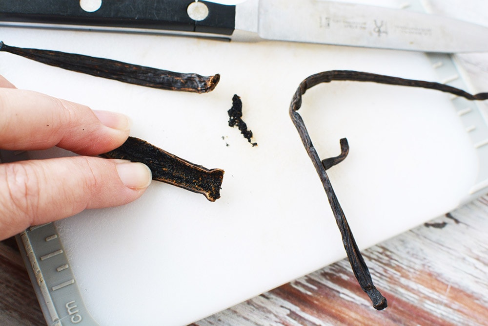 Scraping out a vanilla bean on a cutting board.