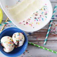 Birthday cake ice cream in a blue bowl next to the scooped out dish