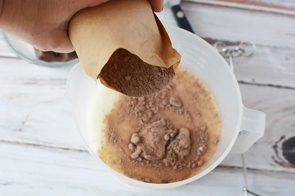 Pouring instant pudding into the milk in a bowl. 