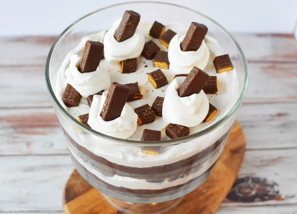 Top of a layered chocolate dessert with whipped cream and cookies. 