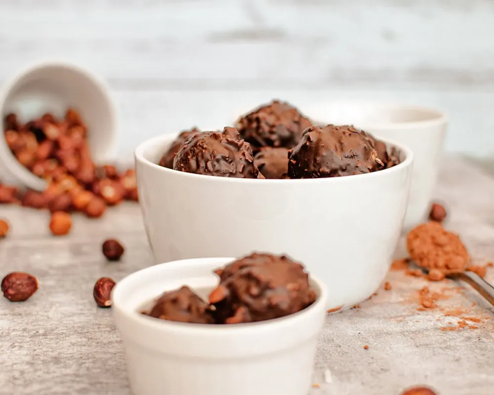 Date balls in a bowl with hazelnuts and other ingredients.