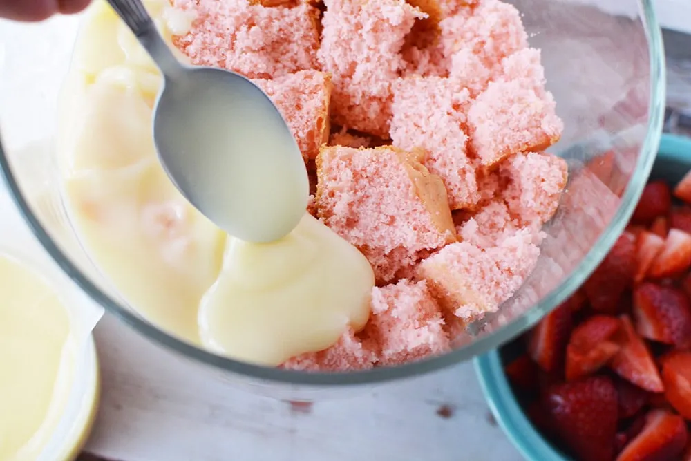 Layering pudding onto strawberry cake in a trifle.