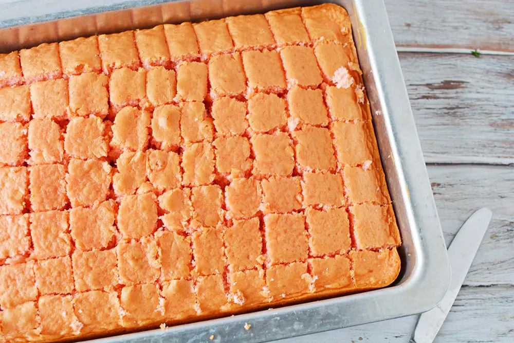 Baked strawberry cake in a pan cut into cubes.