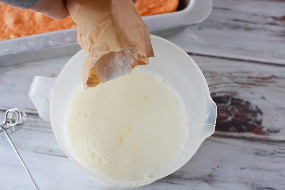 Adding pudding mix into bowl with milk.