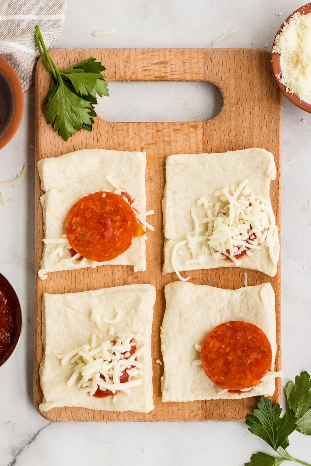 Unrolled pizza pockets with ingredients on a board.