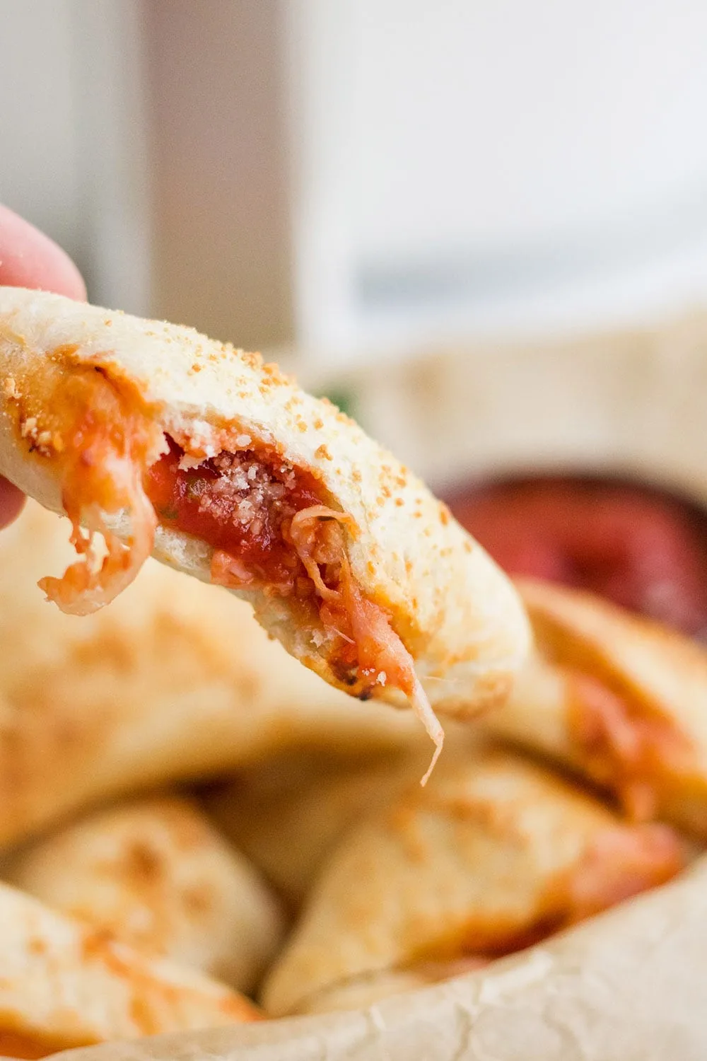 Bite out of a pizza roll showing sauce and cheese.