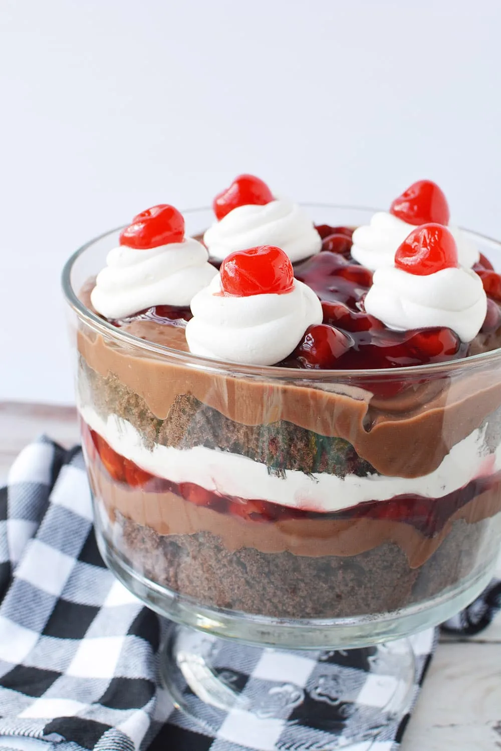 Black forest trifle in a bowl on a table with a checkered napkin.