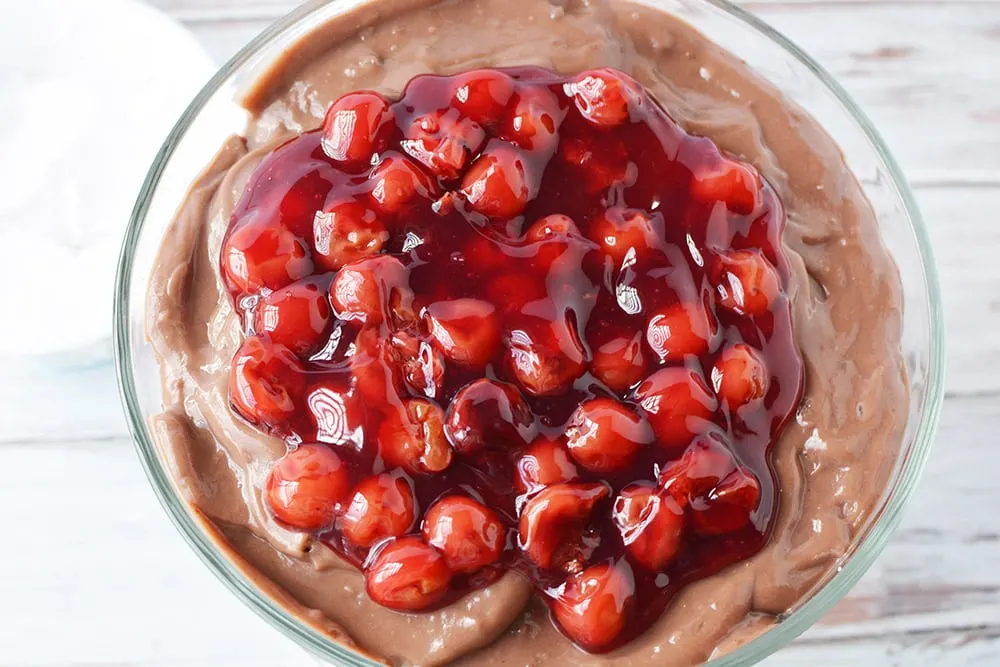 Top of a black forest trifle with cherry filling on top.