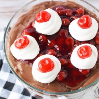 Top of a chocolate cherry trifle with cherries on top of whipped cream.