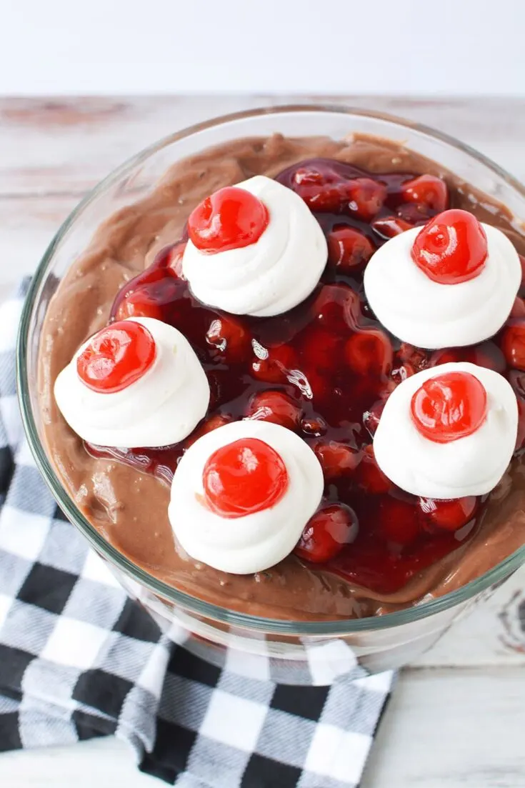 Top of a chocolate cherry trifle with cherries on top of whipped cream.