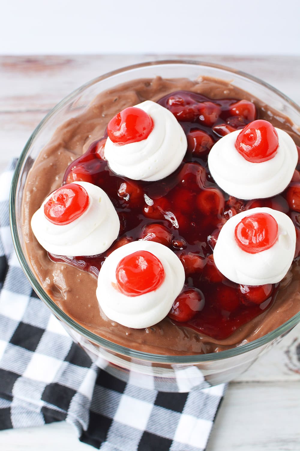 Top of a chocolate cherry trifle with cherries on top of whipped cream. 