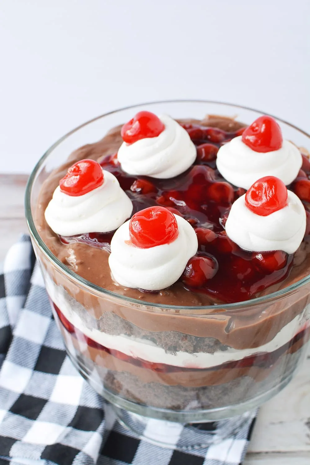 Chocolate cherry trifle in a bowl on a table with blue and white napkin.