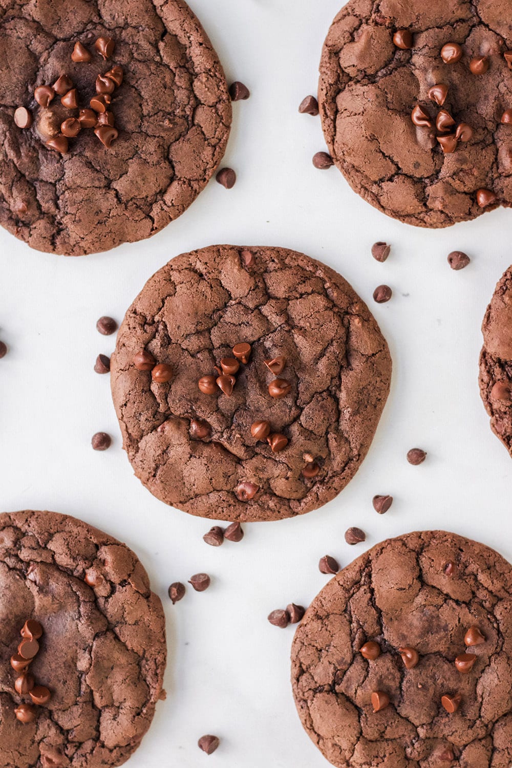 Overhead shot of brownie mix cookies and chocolate chips on a white table.