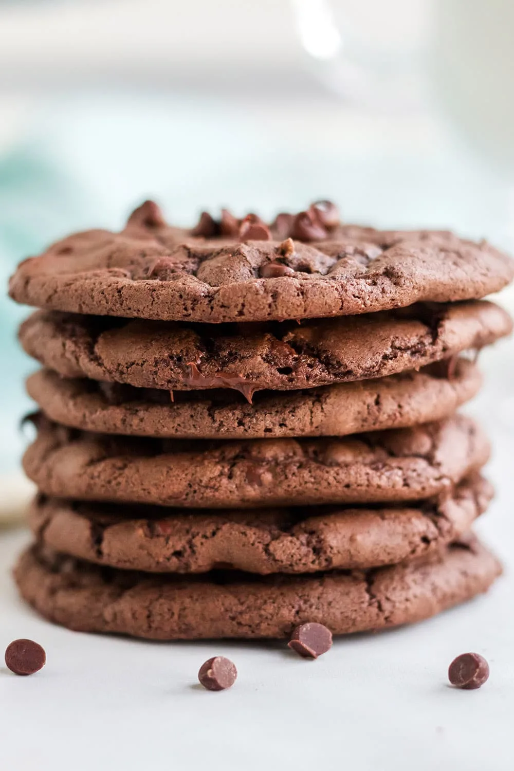 Stack of brownie cookies with chocolate chips on a white table with a blue napkin.
