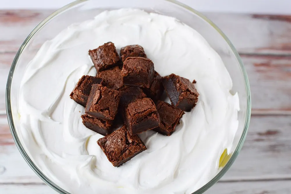 Brownies on top of whipped cream in a trifle.