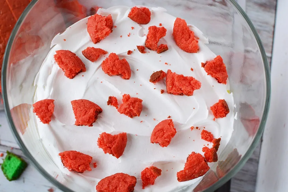 Red cookie pieces on top of whipped cream in trifle.