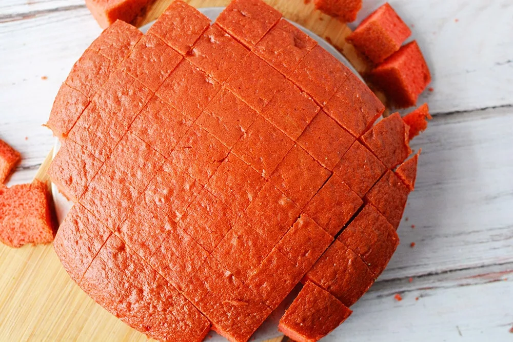 Red round cake sliced into square cubes.