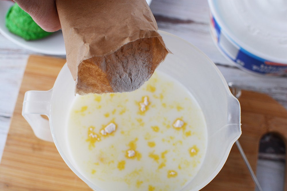 Pudding mix into milk in a bowl.