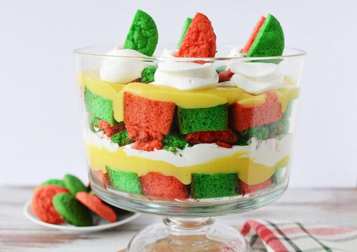 Layers of pudding, green and red cake, cookies, and whipped cream for a Christmas trifle