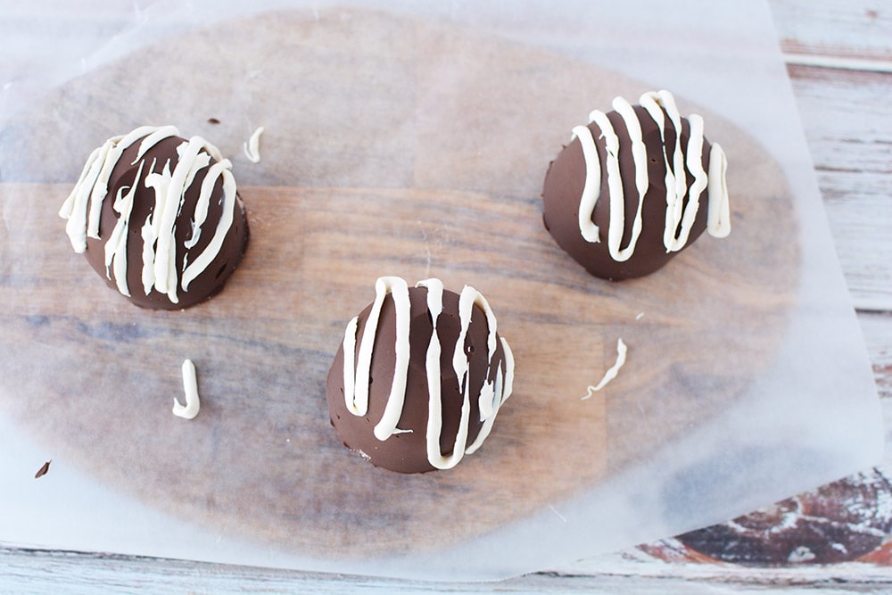 Drizzling white chocolate over hot cocoa bombs.