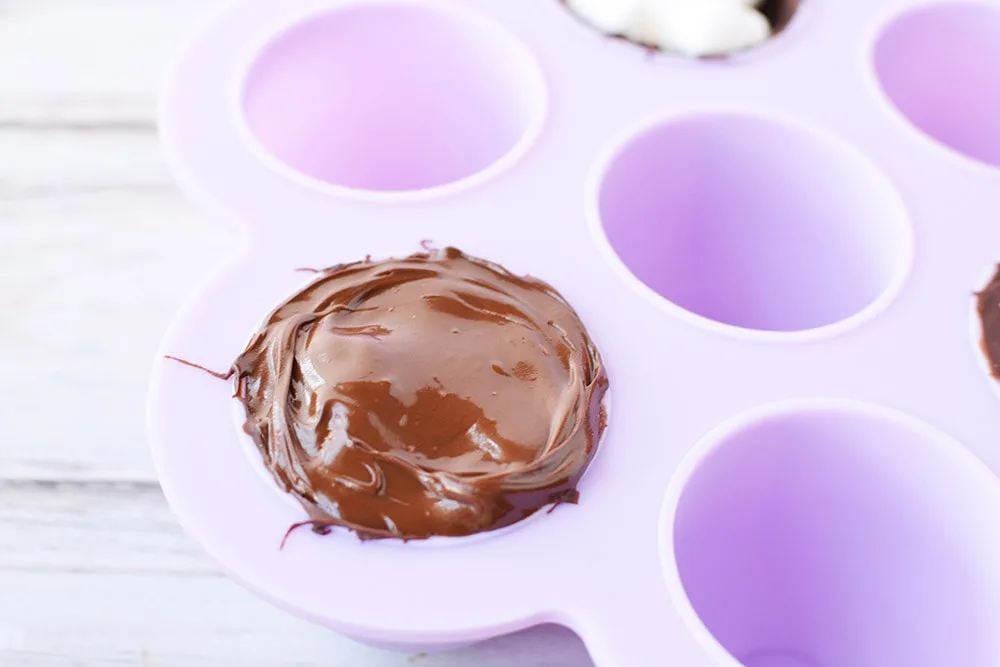 Covering hot chocolate bomb with more chocolate in candy mold