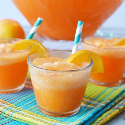 Glasses of orange punch around bowl.