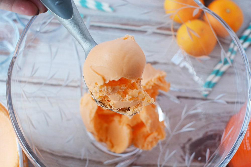 Scooping orange sherbet into punch bowl. 