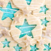 Stained-glass candy cookies with blue stars in different sizes on a white plate.