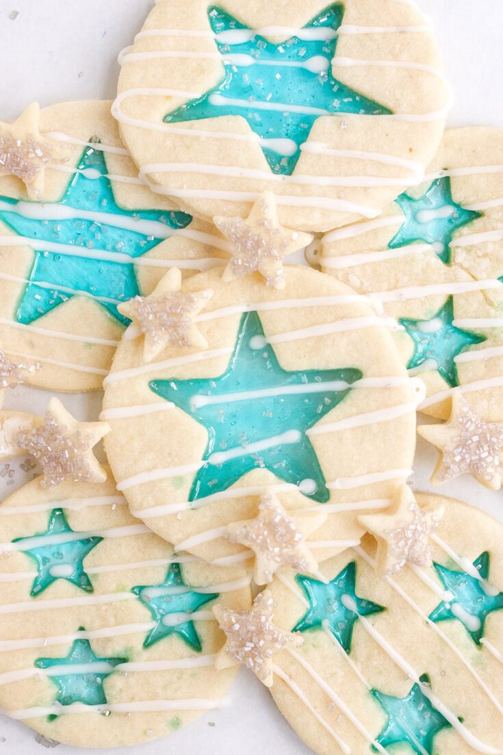 Stained-glass candy cookies with blue stars in different sizes on a white plate.