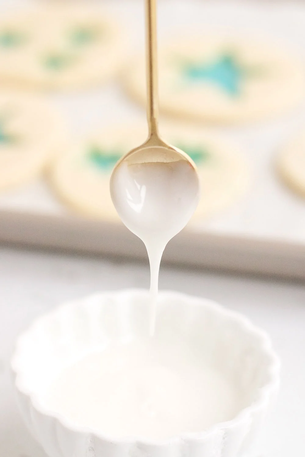 Glaze for Jolly Rancher cookies dripping off a tiny gold spoon. 