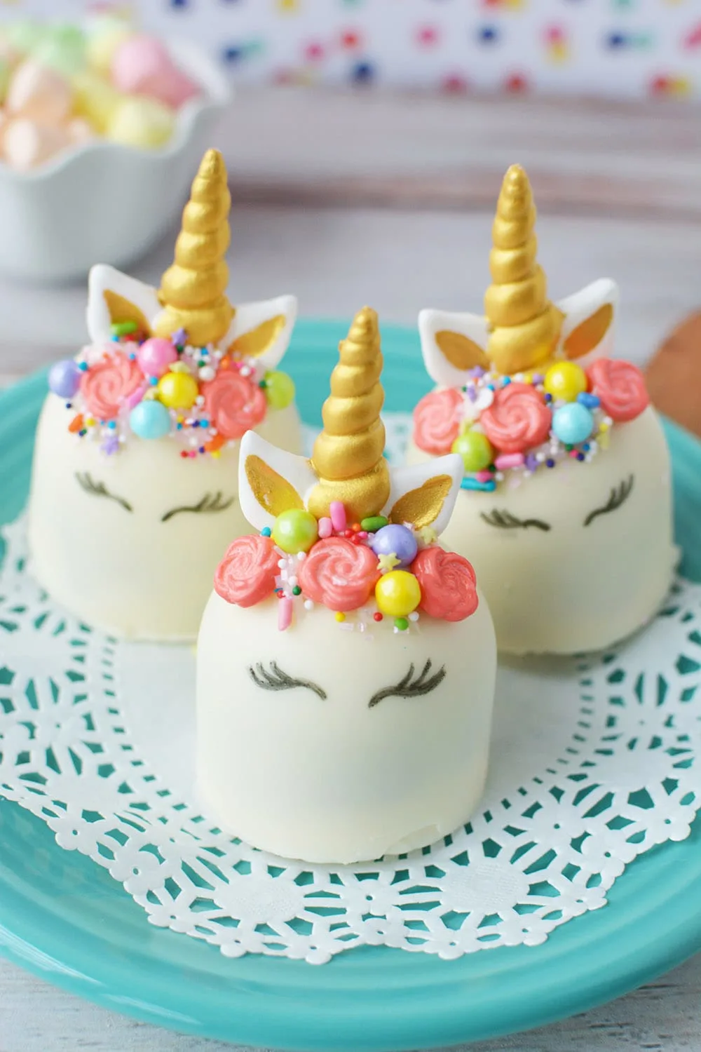 Three white unicorn hot chocolate bombs with faces, horns, ears, and manes. 