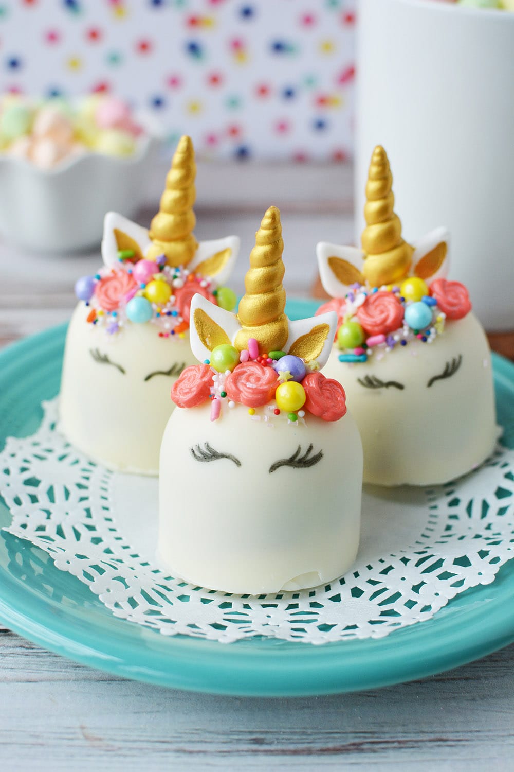 Unicorn hot cocoa bombs sitting on a blue plate. 