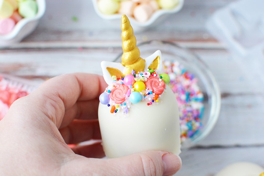 Unicorn hot chocolate bomb with a gold horn and sprinkle mane.