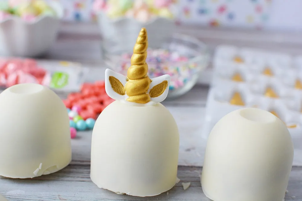 White unicorn hot chocolate bomb with gold horn and ears.