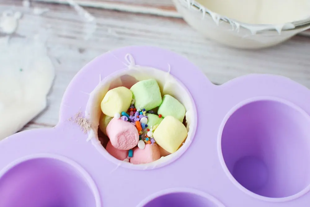 Colored marshmallows and sprinkles in hot chocolate bomb mold.
