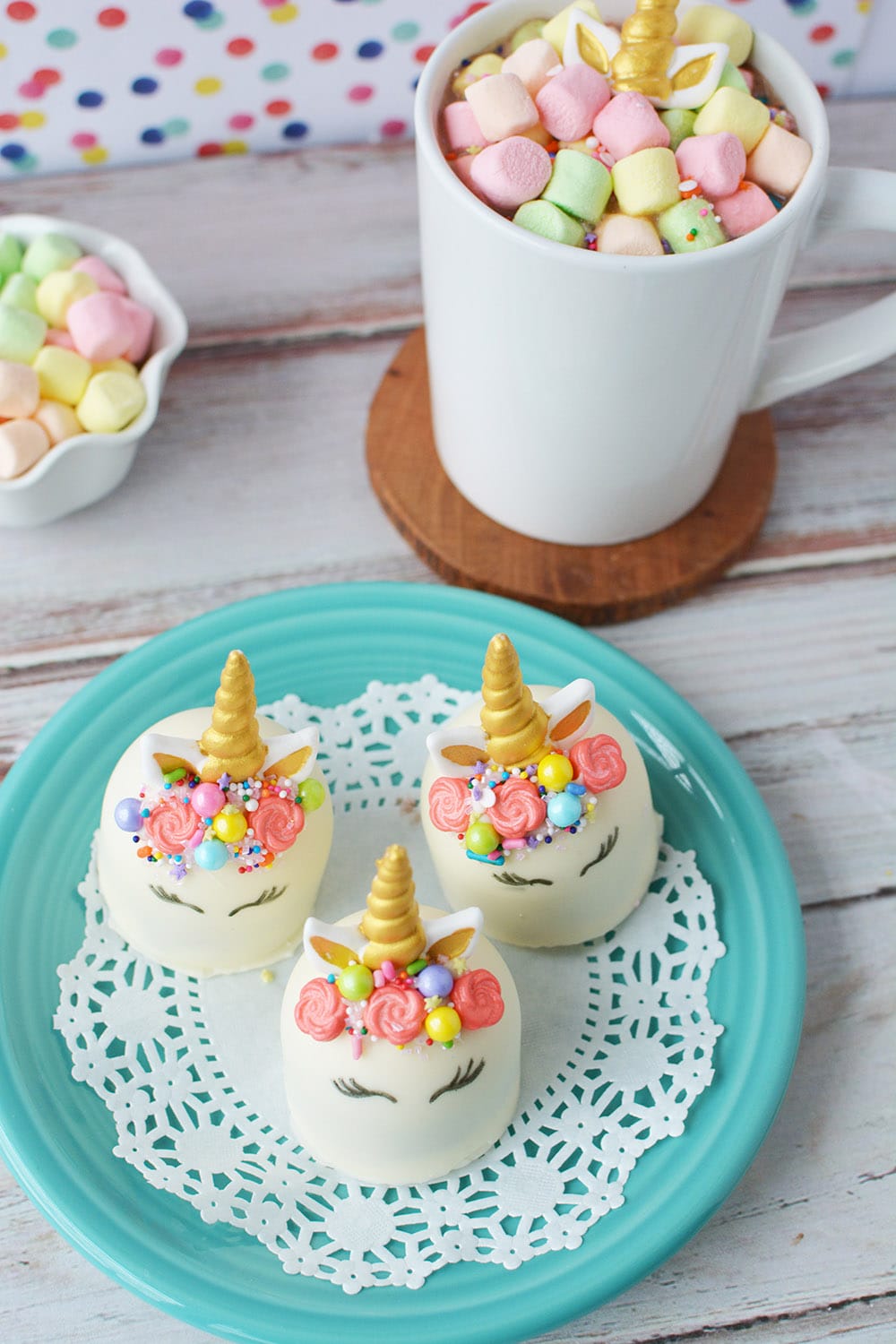Unicorn hot chocolate bombs on a blue plate buy finished hot chocolate with colored marshmallows.