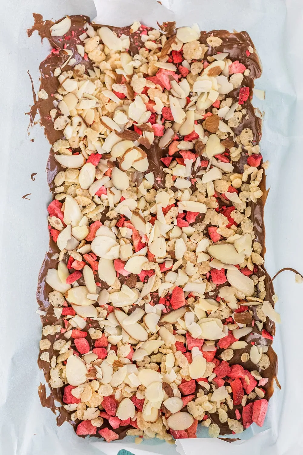 Chocolate bark candy with almonds and strawberries in a pan.