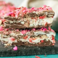 Pieces of strawberry chocolate bark candy stacked on a board.