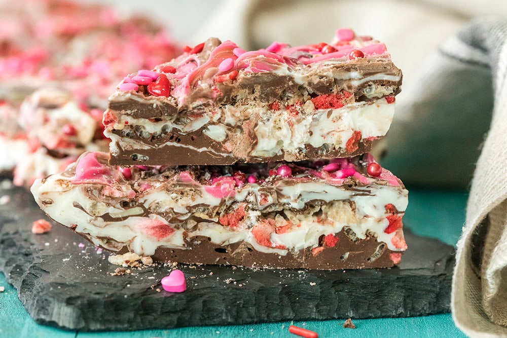 Pieces of strawberry chocolate bark candy stacked on a board.