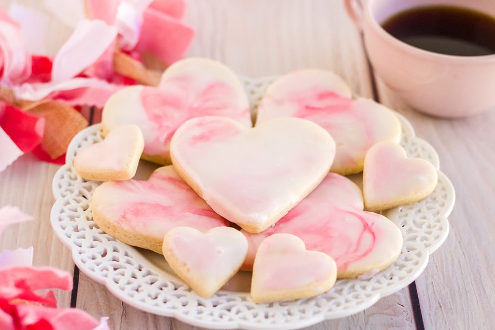 Heart cookies with marble icing with pin decorations on the table.