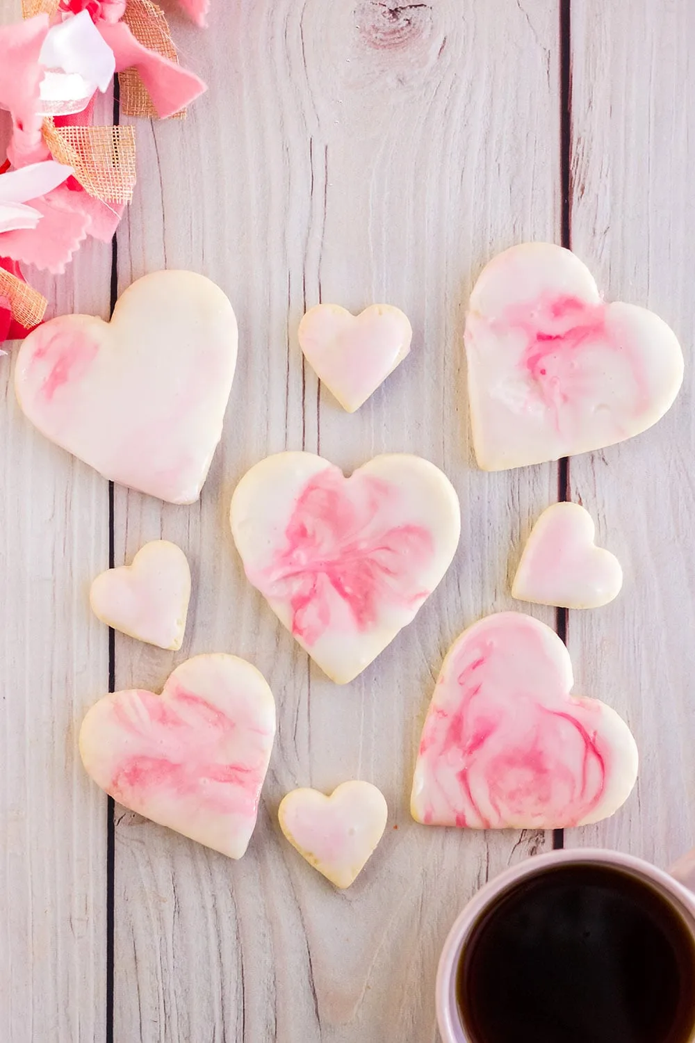 Valentine sugar cookies with pink icing on a board.