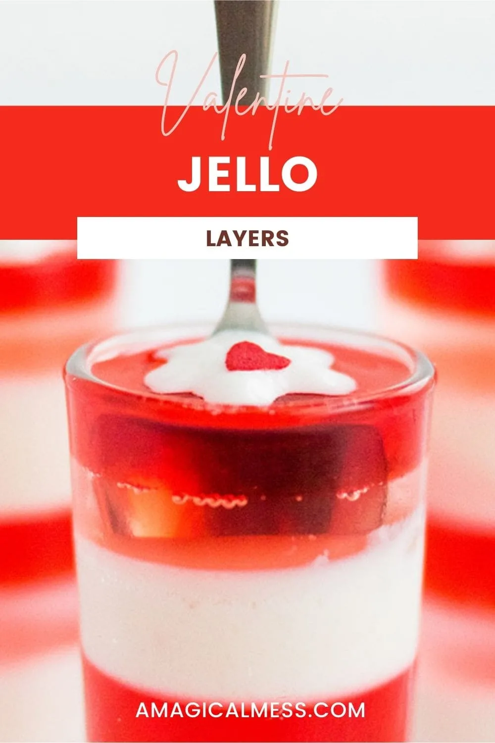 A spoon in a glass of layered jello topped with a tiny bit of whipped cream.